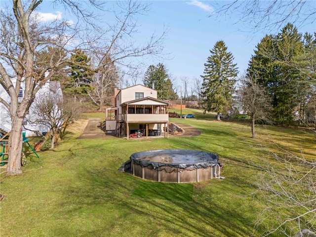 view of yard featuring a sunroom and a covered pool