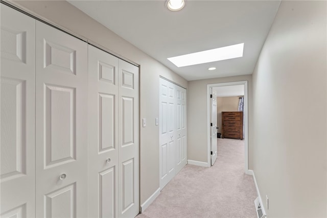 hallway featuring light colored carpet and a skylight