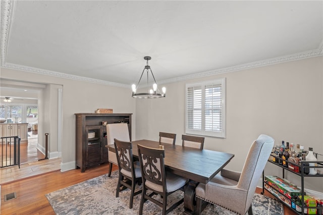 dining space with crown molding, ceiling fan with notable chandelier, light hardwood / wood-style flooring, and a wealth of natural light