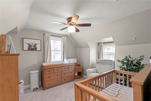 carpeted bedroom featuring a crib, ceiling fan, lofted ceiling, and a textured ceiling