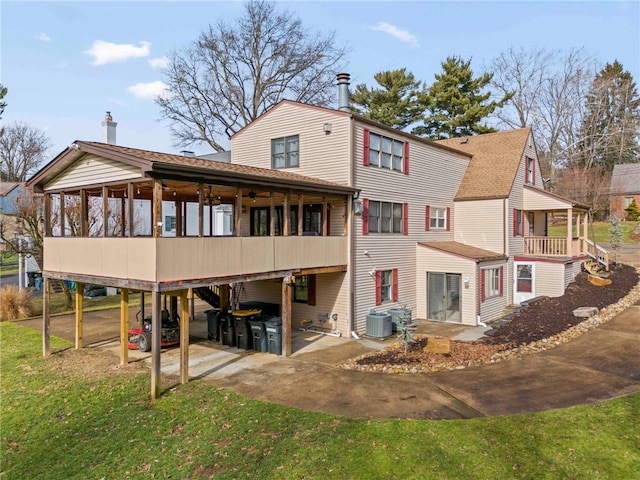 rear view of house featuring a lawn, a sunroom, and central air condition unit