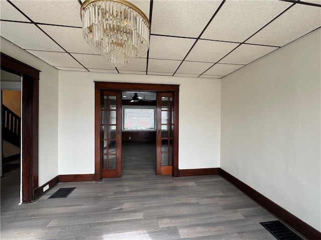 interior space with wood-type flooring, a paneled ceiling, and a notable chandelier