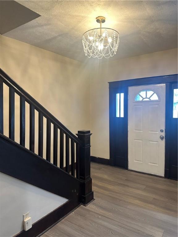 foyer featuring wood-type flooring, a chandelier, and a textured ceiling