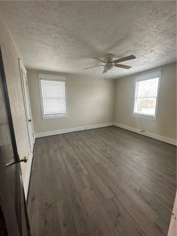 spare room with a textured ceiling and dark hardwood / wood-style flooring