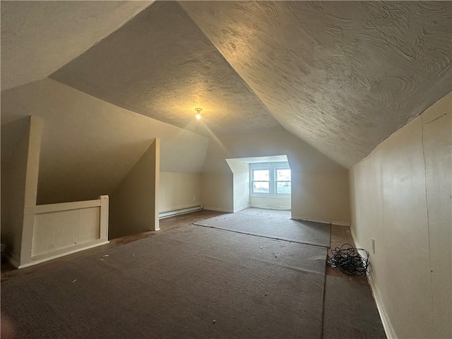 additional living space with a baseboard heating unit, vaulted ceiling, and a textured ceiling