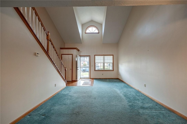 carpeted foyer entrance with high vaulted ceiling