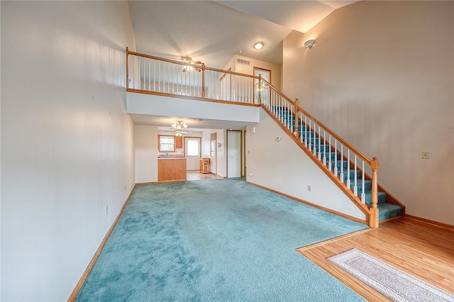 unfurnished living room featuring ceiling fan, carpet flooring, and high vaulted ceiling