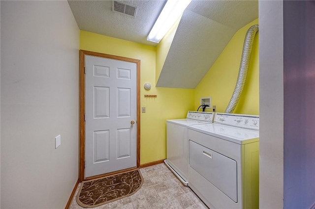 clothes washing area with washer and dryer and a textured ceiling