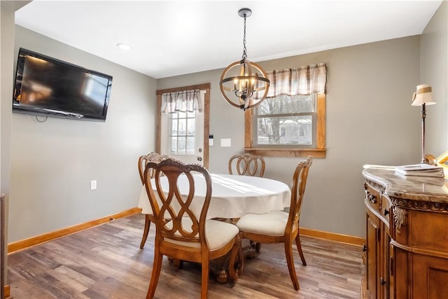 dining space featuring wood-type flooring and a notable chandelier