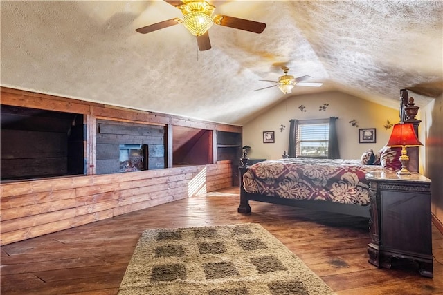 bedroom with ceiling fan, lofted ceiling, dark hardwood / wood-style floors, and a textured ceiling