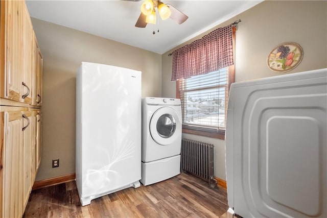 laundry room with radiator, cabinets, hardwood / wood-style flooring, ceiling fan, and washer and clothes dryer