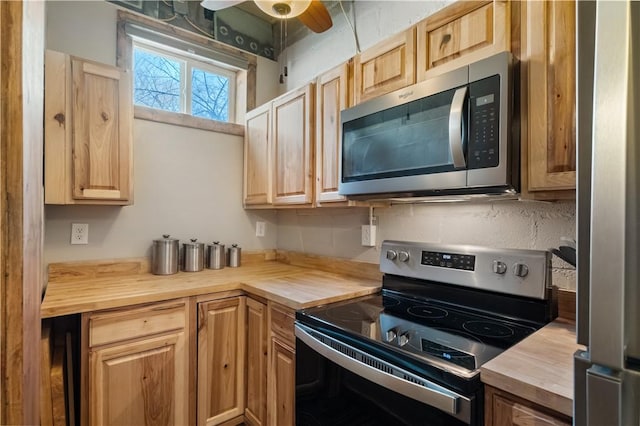 kitchen featuring ceiling fan, stainless steel appliances, and butcher block counters