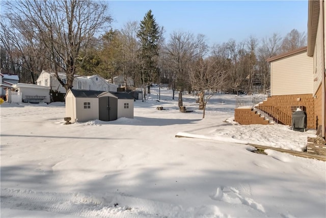 snowy yard featuring a storage unit