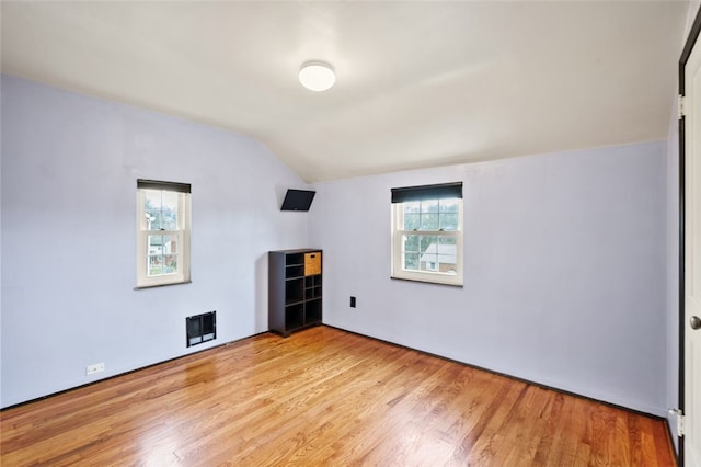 spare room with lofted ceiling and light wood-type flooring