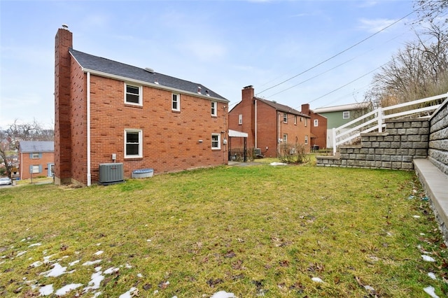 rear view of house featuring central AC and a lawn