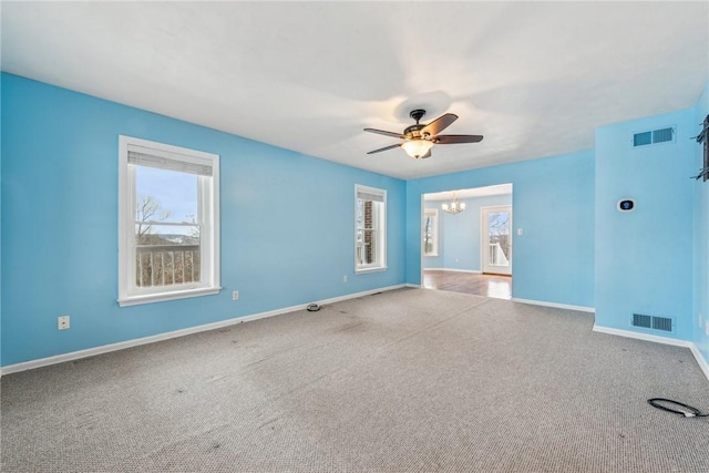 spare room with light colored carpet, plenty of natural light, and ceiling fan with notable chandelier