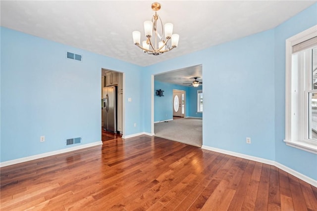 spare room featuring hardwood / wood-style flooring, a healthy amount of sunlight, and an inviting chandelier