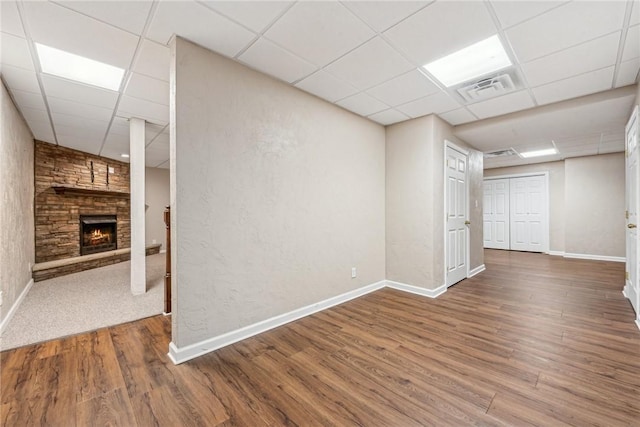 spare room featuring hardwood / wood-style floors, a stone fireplace, and a paneled ceiling