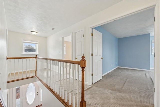 corridor with light colored carpet and a textured ceiling