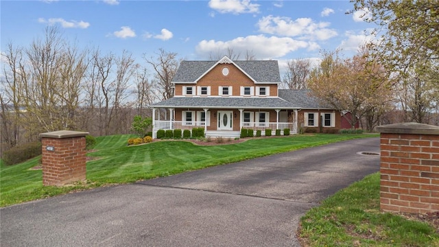 view of front of property featuring brick siding, a porch, and a front yard