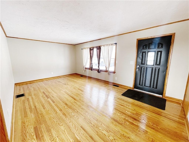 foyer entrance featuring hardwood / wood-style floors, crown molding, and a textured ceiling