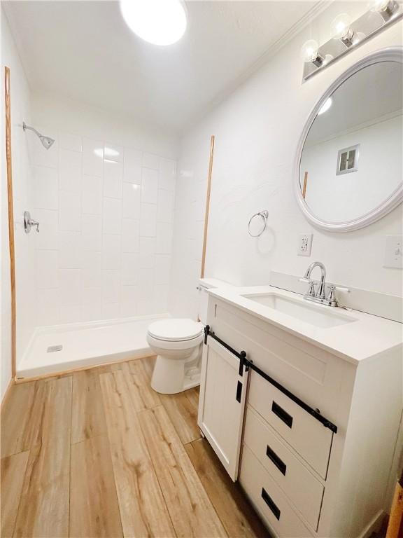 185 Holly Ln, Somerset Twp, PA 15501 - full bathroom with vanity, toilet, wood finished floors, and a tile shower