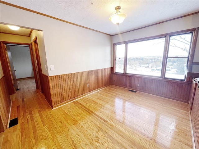 185 Holly Ln, Somerset Twp, PA 15501 - spare room with light wood-style floors, a wainscoted wall, crown molding, wooden walls, and a textured ceiling