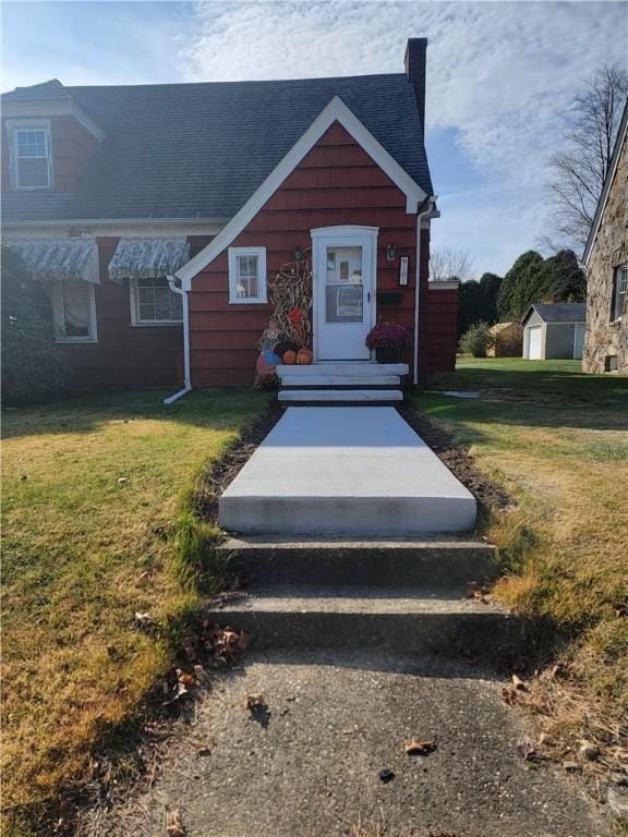 view of front of home featuring a storage unit and a front lawn