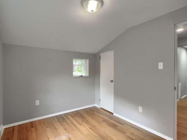 spare room featuring hardwood / wood-style flooring and lofted ceiling