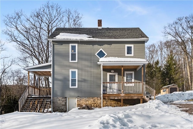 snow covered rear of property with covered porch