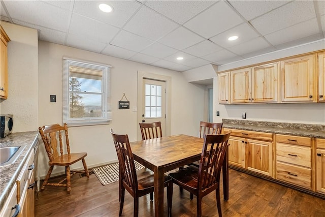 dining space with sink, dark wood-type flooring, and a paneled ceiling