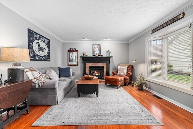 living room with hardwood / wood-style flooring, a fireplace, ornamental molding, and a textured ceiling