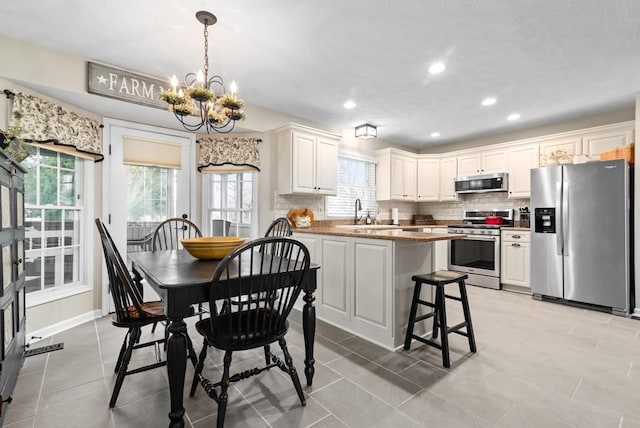 kitchen featuring decorative light fixtures, sink, decorative backsplash, a notable chandelier, and stainless steel appliances