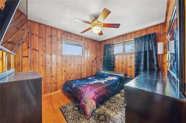 bedroom with hardwood / wood-style flooring, ceiling fan, and wood walls