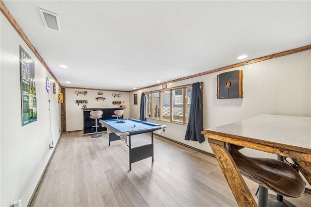 playroom with bar, crown molding, pool table, and light wood-type flooring