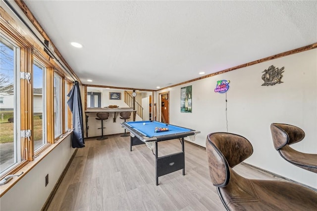 rec room with pool table, ornamental molding, light hardwood / wood-style floors, and a textured ceiling