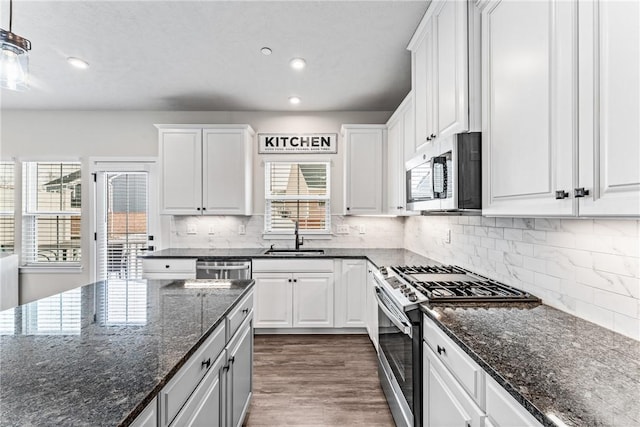 kitchen featuring appliances with stainless steel finishes, tasteful backsplash, white cabinetry, sink, and dark stone counters