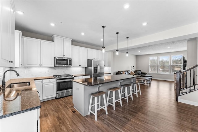 kitchen featuring pendant lighting, sink, white cabinetry, stainless steel appliances, and a center island