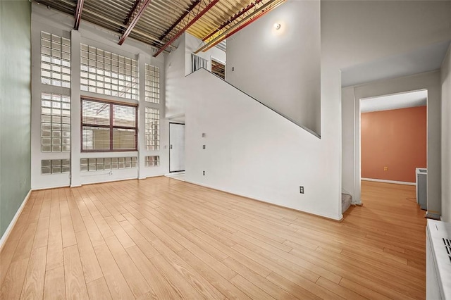 unfurnished living room featuring light hardwood / wood-style flooring and a high ceiling