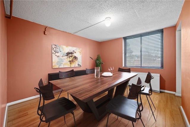 dining space with a textured ceiling and light hardwood / wood-style flooring