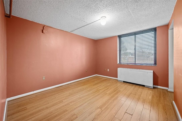 empty room with radiator, a textured ceiling, and light wood-type flooring