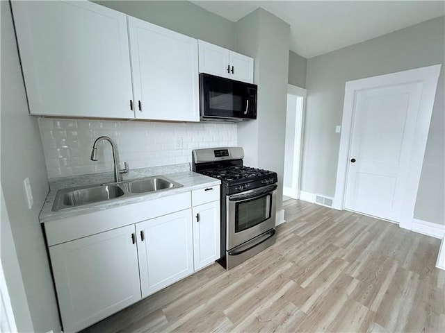 kitchen with sink, stainless steel gas range, tasteful backsplash, light hardwood / wood-style floors, and white cabinets