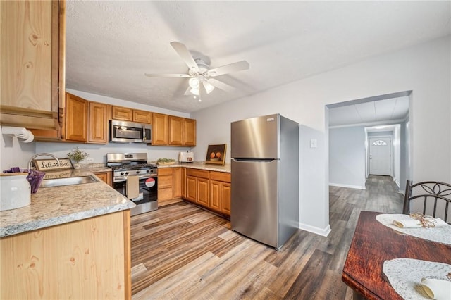 kitchen featuring hardwood / wood-style flooring, ceiling fan, appliances with stainless steel finishes, and sink