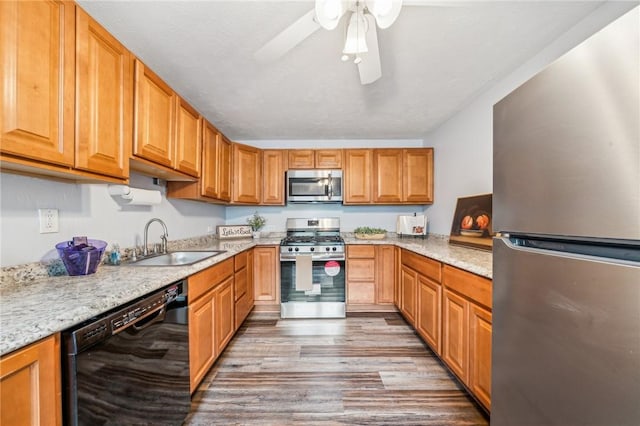 kitchen featuring sink, light stone counters, light wood-type flooring, ceiling fan, and stainless steel appliances