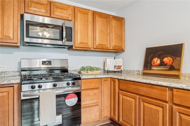 kitchen with light stone counters and appliances with stainless steel finishes