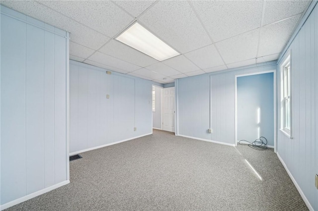 basement with a paneled ceiling and carpet