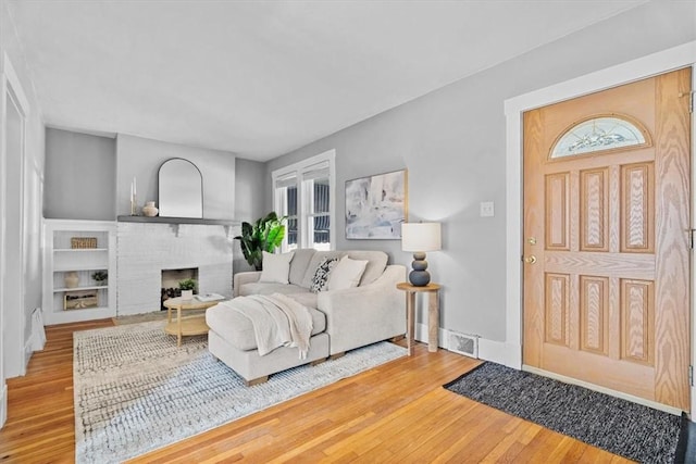 living room with hardwood / wood-style flooring and a brick fireplace