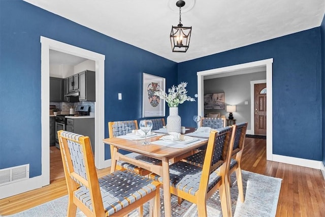 dining area with light hardwood / wood-style flooring and a chandelier