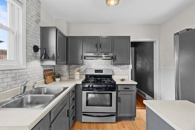 kitchen featuring gray cabinets, sink, decorative backsplash, stainless steel appliances, and light hardwood / wood-style flooring