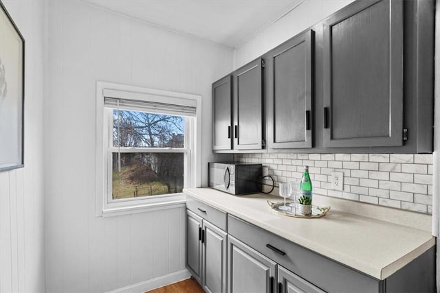 kitchen with tasteful backsplash, light hardwood / wood-style floors, and gray cabinetry